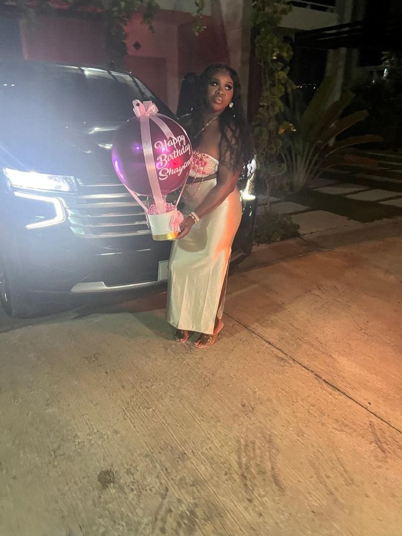 Guest with a pink birthday balloon beside a Layla SUV at night